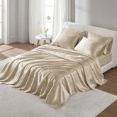 Beige satin bedding set on a bed in a bright bedroom.