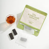 Green tea brick with tea bags and a glass of tea on a white background