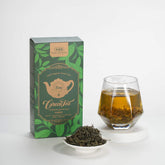 Tea packaging with a glass of tea and a bowl of loose tea leaves on a white background