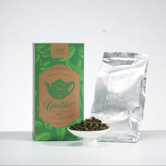 Tea packaging with a green label and a clear container of tea leaves on a white background