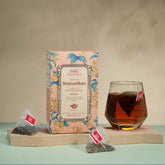 Tea packaging with a glass of tea on a wooden tray against a beige background