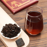 Tea leaves, a glass of tea, and a tea box on a wooden surface