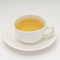White cup and saucer with yellow liquid on a white background