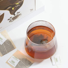 Tea packaging with a glass of tea and tea bags on a white background