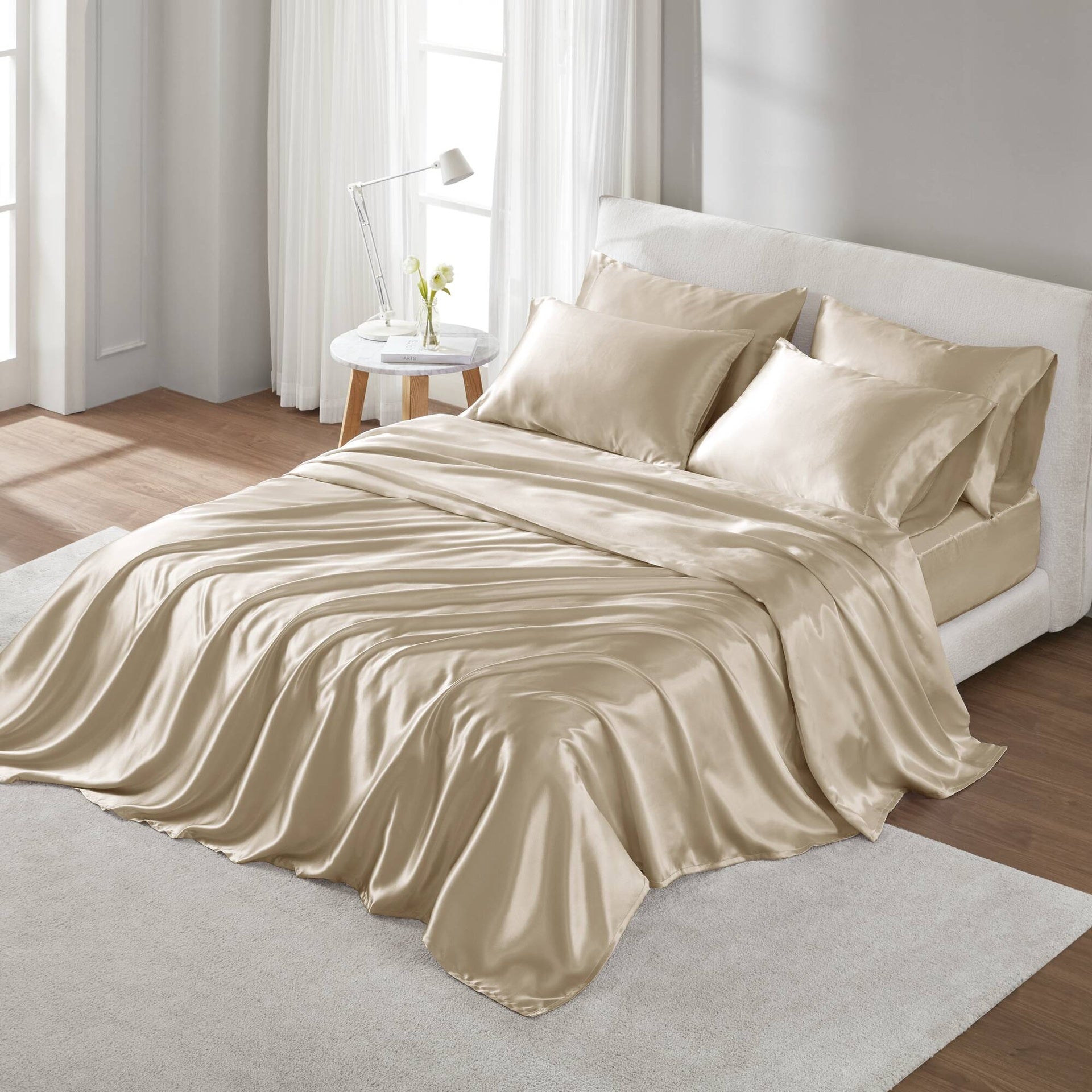 Beige satin bedding set on a bed in a bright bedroom.