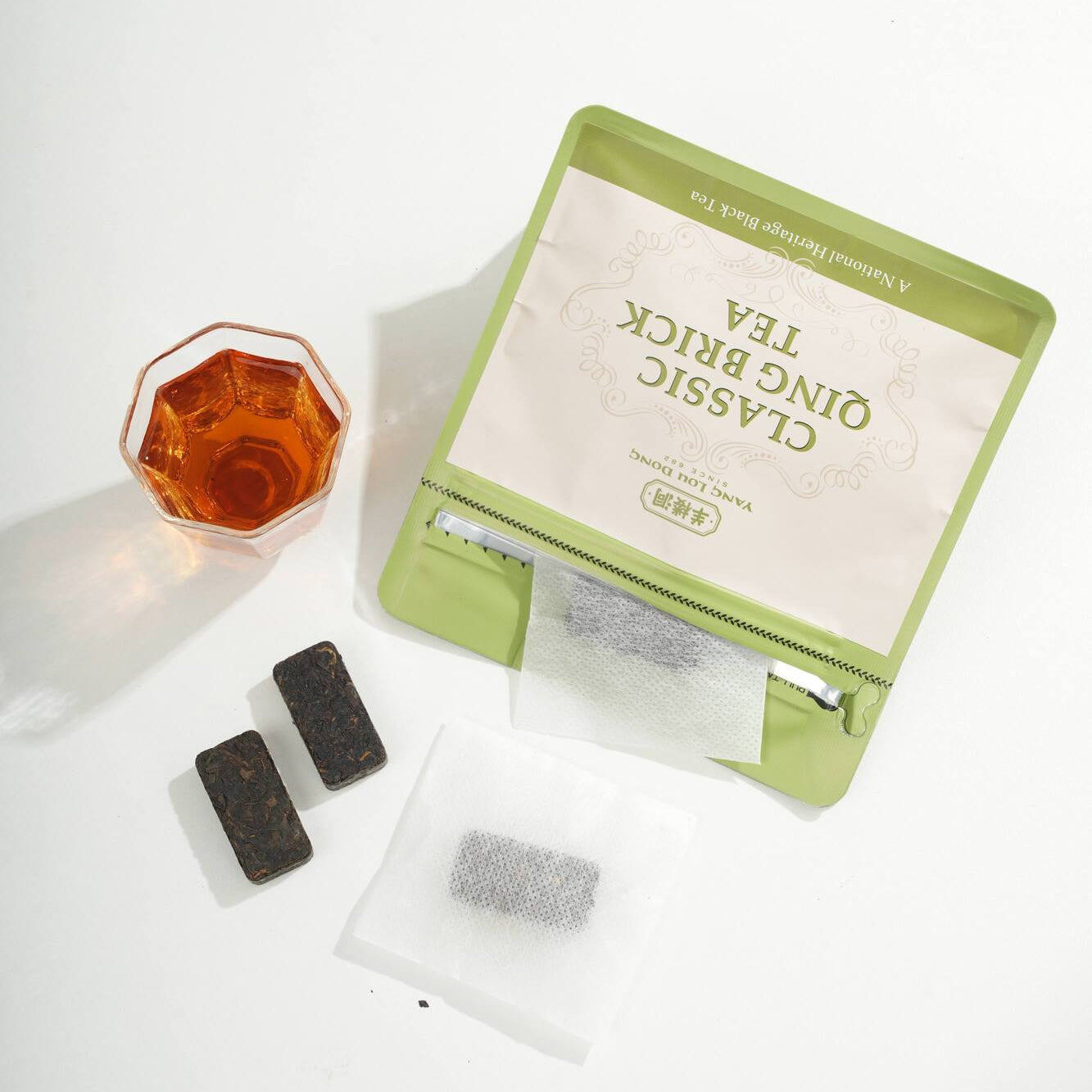 Green tea brick with tea bags and a glass of tea on a white background