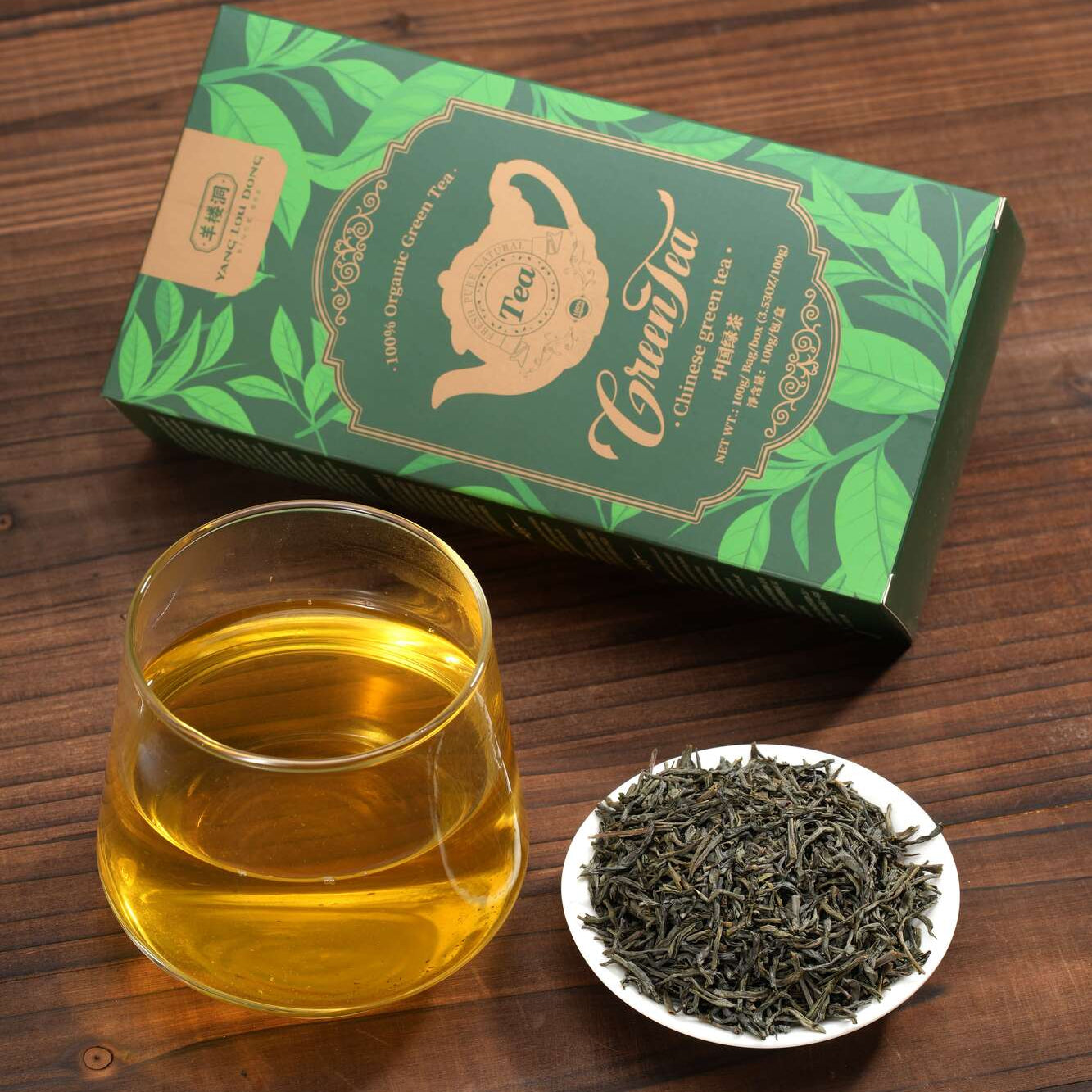 Tea packaging, glass of tea, and tea leaves on a wooden surface