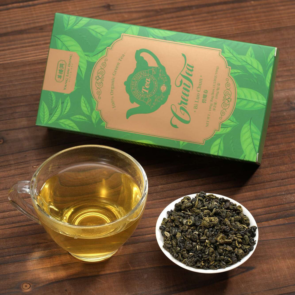 Tea packaging, cup of tea, and bowl of tea leaves on a wooden surface