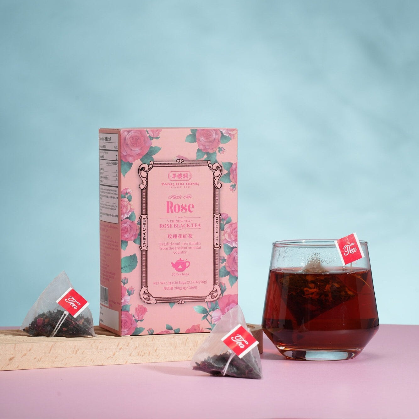 Tea packaging with a glass of tea on a pink surface against a light blue background