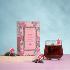Tea packaging with a glass of tea on a pink surface against a light blue background