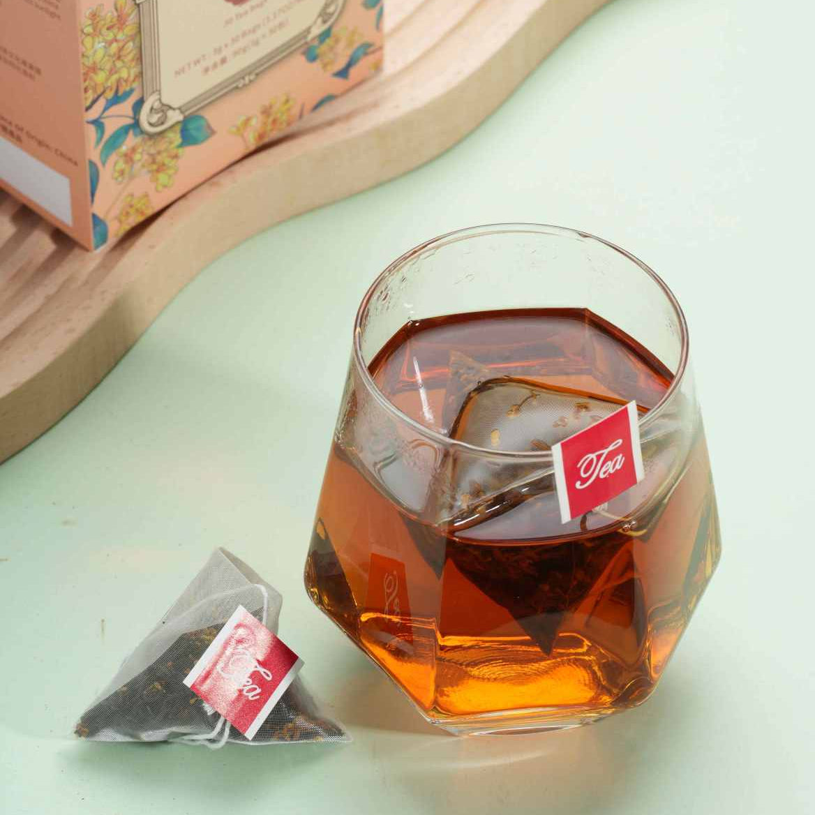 Glass of iced tea with tea bags and packaging on a light green surface