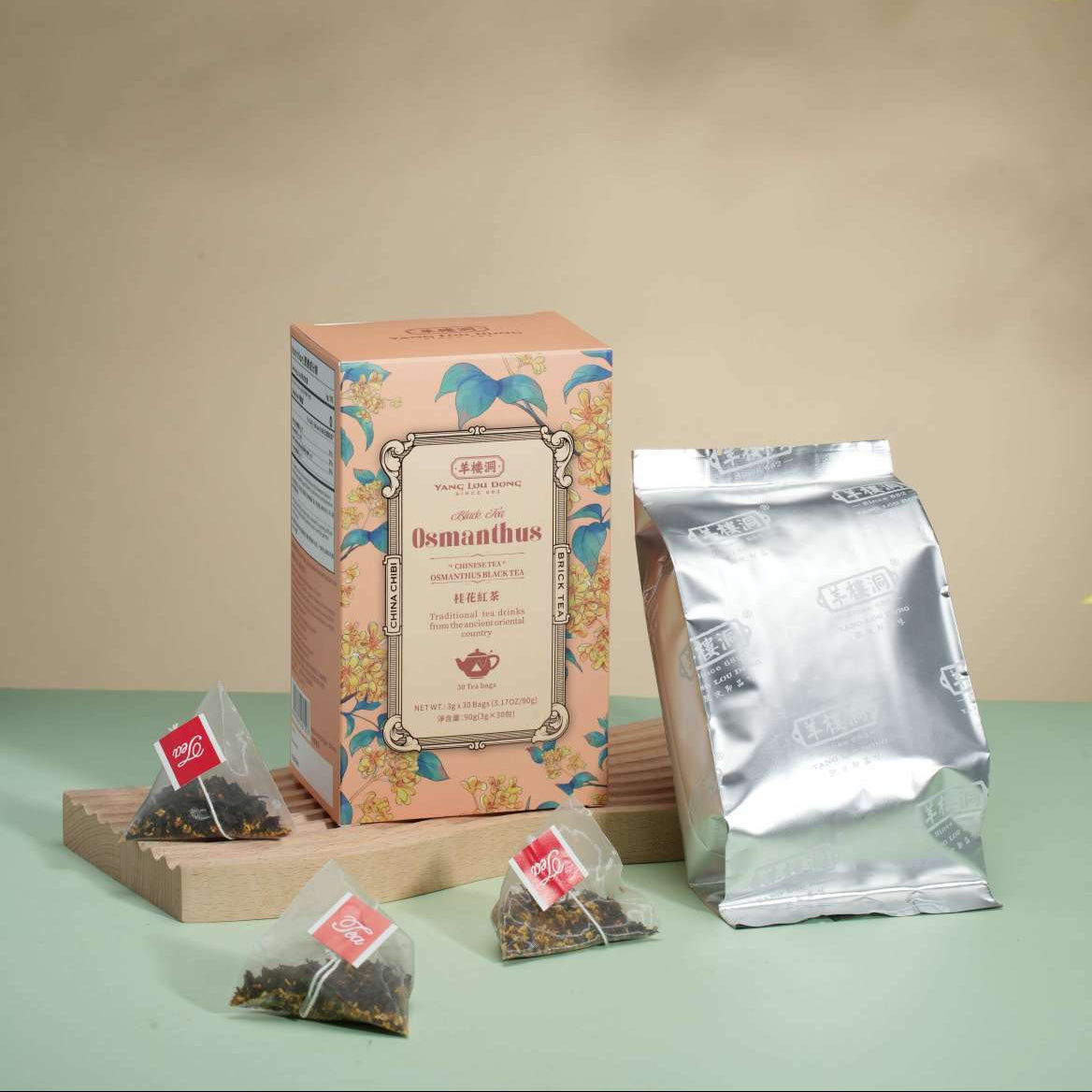 Tea packaging including a box, bags, and a silver package on a green surface with a beige background.