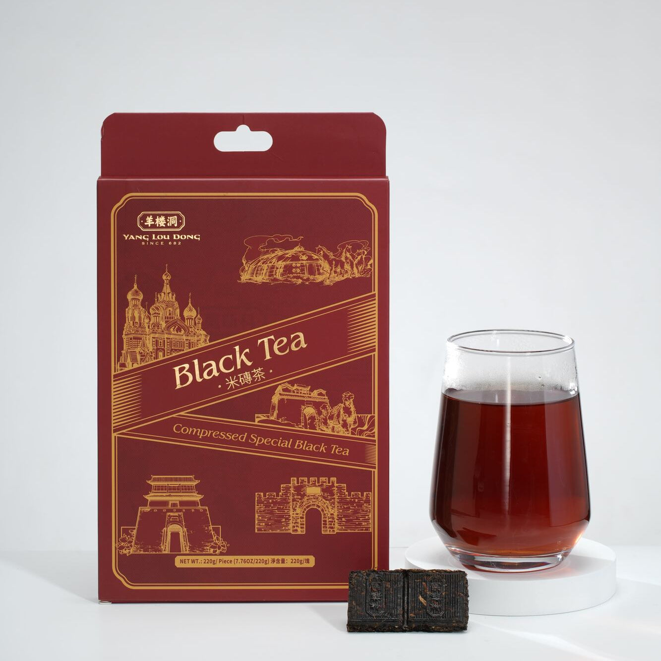 Red package of black tea with a glass of tea and tea brick on a white background