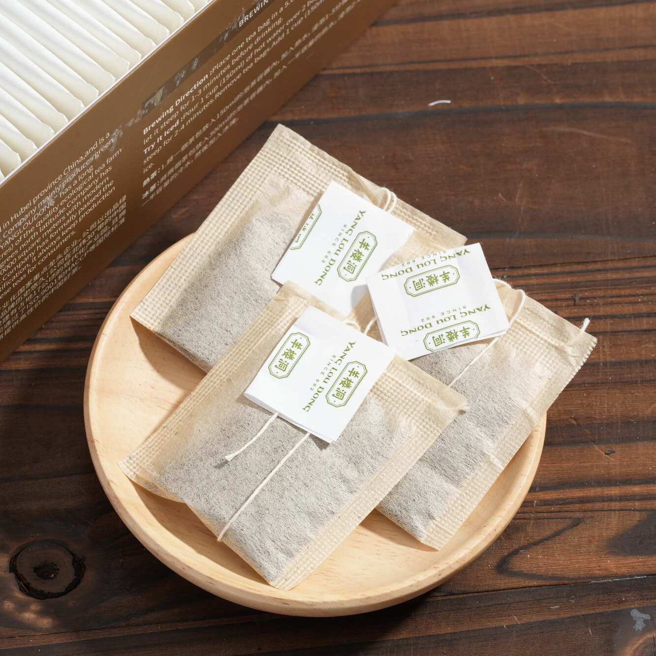 Tea bags with labels on a wooden plate on a wooden surface